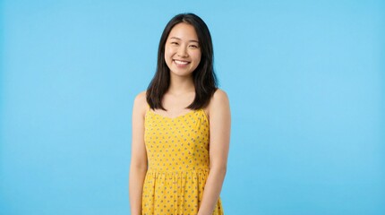 Happy Young Asian Woman in Yellow Dress Smiling on Blue Background