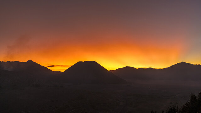 Aerial view of the Bromo-Tengger-Semeru National Park as the sun paints the sky with fiery hues over the volcanic landscape, Probolinggo, East Java, Indonesia.