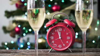 Celebration with clock and glasses at a holiday gathering near a decorated tree with lights and ornaments