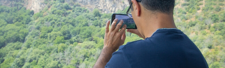 Man taking picture in nature by smartphone.