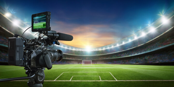 video camera on a tripod with soccer stadium background
