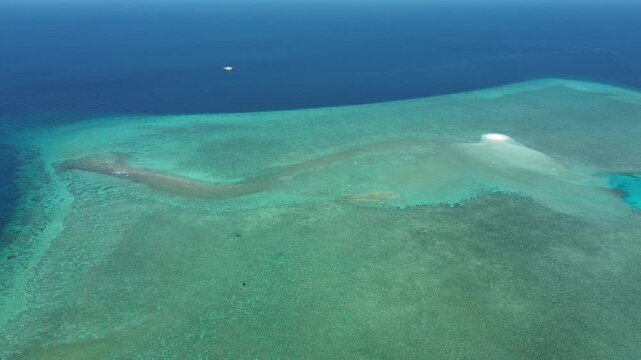 Aerial view of coral reef flat surrounding a sandbar island in clear waters near Nil Desperandum, Banda Sea.