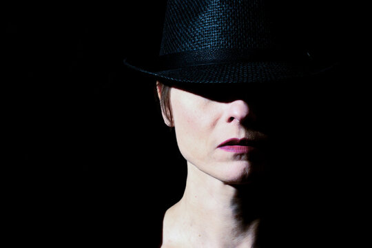 Woman wearing hat in dramatic low key portrait lighting
