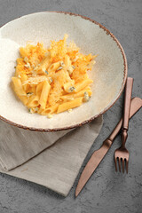 Penne pasta in creamy four-cheese sauce with gorgonzola chunks and crispy parmesan topping in rustic white bowl. Indulgent Italian quattro formaggi dish