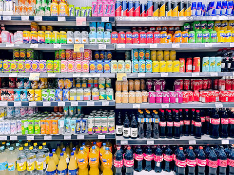 LATVIA, RIGA, 02, JANUARY, 2026: Large section with soda pop drinks on shelves for sale in supermarket. The assortment includes Cola, Chupa Chups, Shweppes and other drinks.