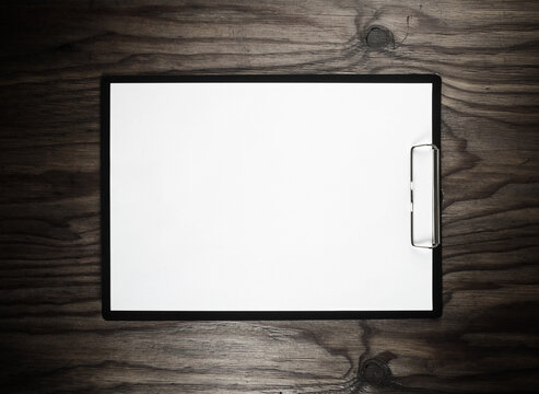 Clipboard with blank A4 paper on wooden surface with plenty of copy space. Branding stationery mockup. Flat lay.