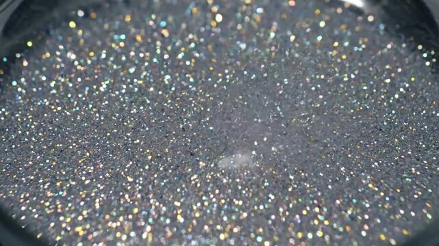 Sparkling Fluid Motion Macro shot of iridescent glitter suspended in a clear liquid, slowly swirling to create dynamic caustic light patterns.