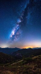 Stunning long exposure photograph capturing the Milky Way above dark, forested mountains at twilight.
