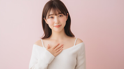 Young Japanese woman with hand on chest looking at camera on pastel pink background