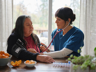 Native American nurse listens while taking elderly patient's blood pressure