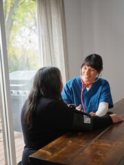 Native American nurse and patient sit at table to check blood pressure