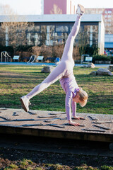 Child doing handstand exercise in park on sunny day