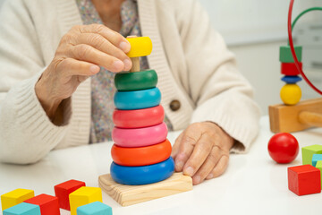 Asian elderly woman playing enhancing skill board game.