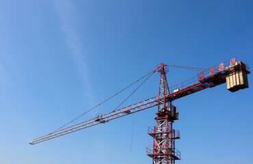 Construction crane against clear blue sky, industrial equipment for building projects, development and infrastructure concept with copy space for text.