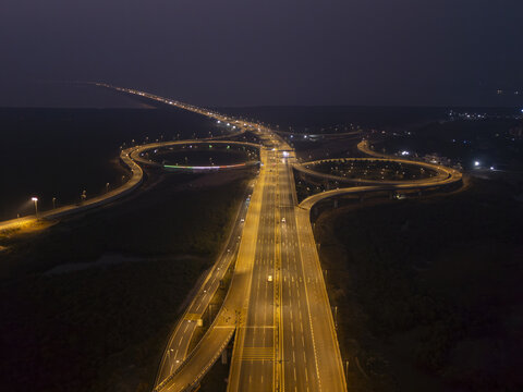 Aerial view of the illuminated Atal Setu bridge cutting through the darkness, a ribbon of light connecting distant shores, Mumbai, Maharashtra, India.