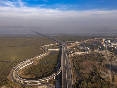 Aerial view of Shri Atal Bihari Vajpayee Trans Harbour Link cutting through marshland towards the city under a clear sky, Mumbai, Maharashtra, India.