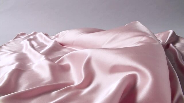 AI, Delicate pink satin silk gently billows on a neutral background. Rosy blush tone, smooth folds ripple, side lighting highlights luster