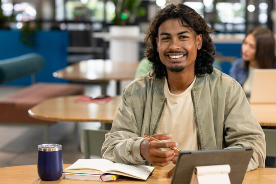 Diverse students studying in study lounge with African American man writing notes tablet travel mug