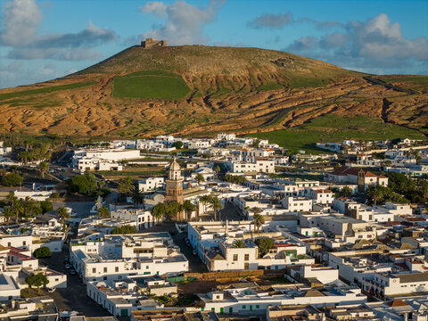 Aerial view of the Castillo de Santa Barbara atop the volcano overlooking the whitewashed village and the golden hills, Teguise, Lanzarote, Spain.