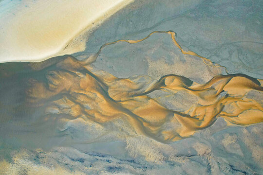 Aerial view of swirling golden sands meet the cool blue waters in intricate patterns, creating a mesmerizing dance of color and texture, Eurong, Queensland, Australia.