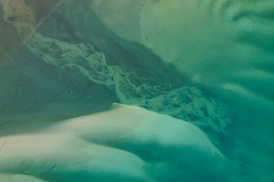 Aerial view of the river carving through the sandy landscape, creating a tapestry of teal and beige hues, Eurong, Queensland, Australia.