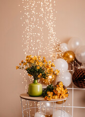 Green vase with yellow flowers and festive lights