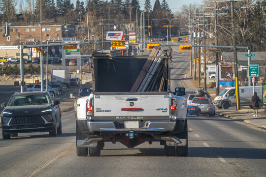 Calgary, Alberta, Canada. April 12, 2023. Rear view of a white Dodge Ram Heavy Duty pickup truck loaded with construction equipment on a city street.