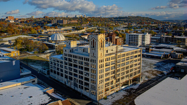 Aerial view of a weathered building with a distinctive tower stands amidst a cityscape touched by early snow, Cincinnati, Ohio, United States.