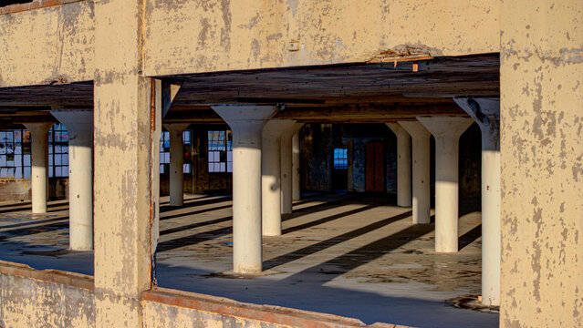 Aerial view of a decaying interior, where light and shadow dance across weathered pillars in a forgotten industrial space, Cincinnati, Ohio, United States.