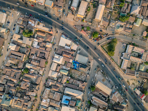 Aerial view of rooftops basking in the golden sunlight, as a long road cuts through the heart of the city, teeming with vehicles, Kaduna, Kaduna, Nigeria.