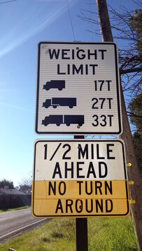 Warning sign on rural road regarding bridge weight restrictions, with  no turn around option.