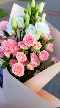 Beautiful bouquet of flowers packaging with pink and white roses on display at a local park in the evening,vertical video
