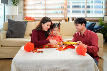 Asian family decorated house for Chinese New Year Celebrations. putting traditional pendant to the...