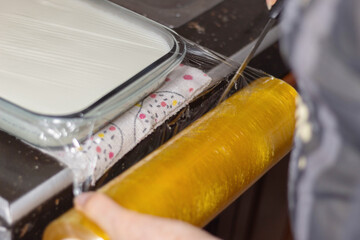 Covering a container with milk preparation with plastic wrap for resting. Healthy homemade recipe