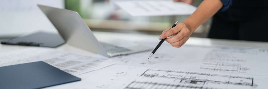 Asian woman architect works on blueprints in a modern office studio