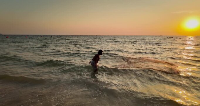 close up of a fisherman casting a net into the sea during a golden sunset. ( in slow motion ) 