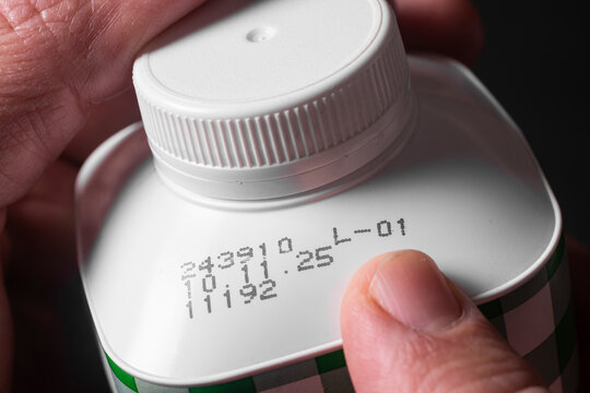 A man checks the production date and expiration date on a package of milk.