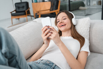 Girl, smartphone and smile with mobile app for listening to music on couch at apartment. Woman,...