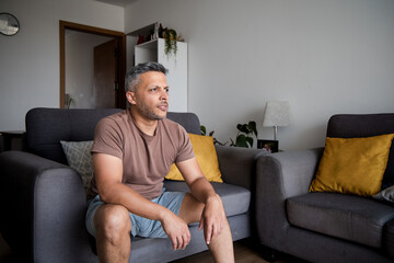 Mature Man Lifting Dumbbells and Exercising on Home Sofa
