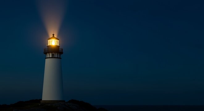 Lighthouse standing alone on rocky coastline emitting bright light beam at night