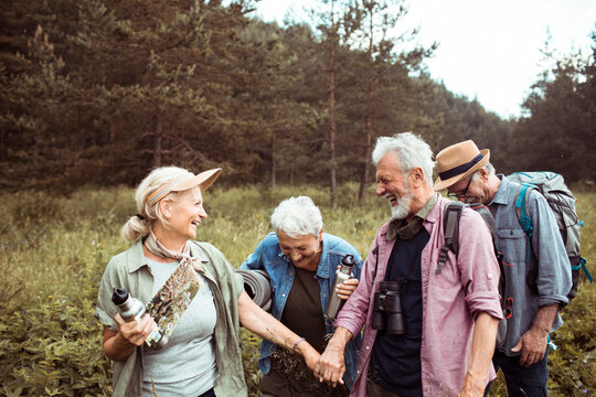 Senior friends hiking and laughing in forest