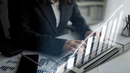 A business professional engages in financial analysis on a laptop, surrounded by modern workspace elements and digital graphs representing market trends and growth. Copula