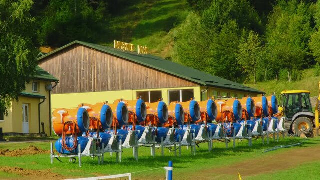Colorful concrete mixers row and excavator near country house on sunny day. Construction site equipment used at resort mountain resort maintenance