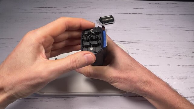 Disassembling a men's electric wireless razor and replacing old batteries - step 10 of 10, part of a series: reassembly phase, repositioning of the swing frame springs and razor function test