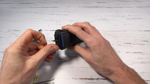 Disassembling a men's electric wireless razor and replacing old batteries - step 3 of 10, part of a series: removal of the screws of the razor head support and part of the support itself