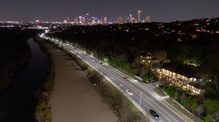 A nighttime bird's-eye view of a highway near a river and a cityscape in cinematic twilight, representing urban mobility and modern infrastructure, for travel, design, and technology presentations.