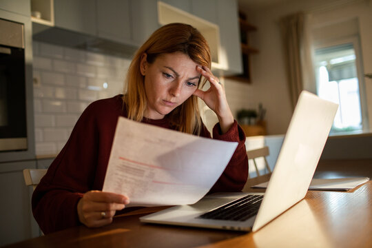 Concerned woman reviewing household bills at kitchen table