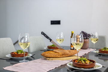 Elegant dining table set with white wine, artisan bread, and gourmet salad in modern interior