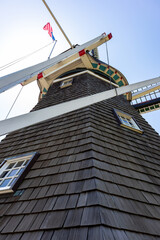 Low angle view of a Dutch style windmill with American Flag against blue sky