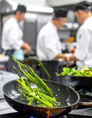 Kitchen staff prepare fresh asparagus in a busy restaurant during peak hours at the vegetable saute station